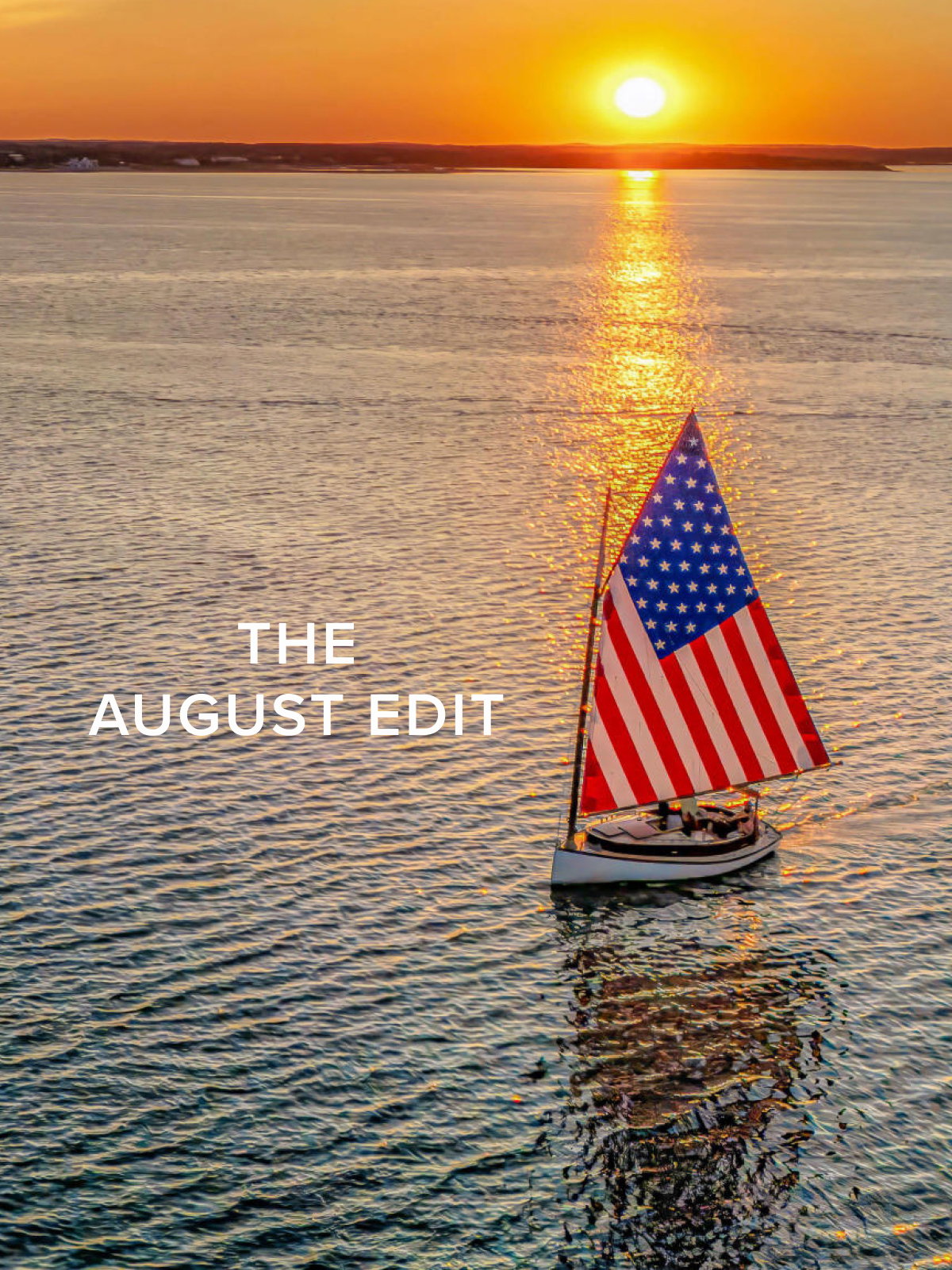 A sail boat with an American flag sail in he water amongst an east coast sunset