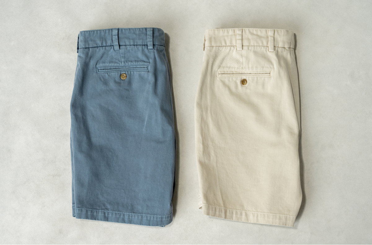 Two pairs of Bills Khakis heriage wash shorts lay on a light surface
