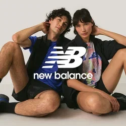Twee jonge volwassenen die op de grond zitten met gebogen benen, gekleed in sportieve casual kleren en sneakers, tegen een eenvoudige lichte achtergrond.