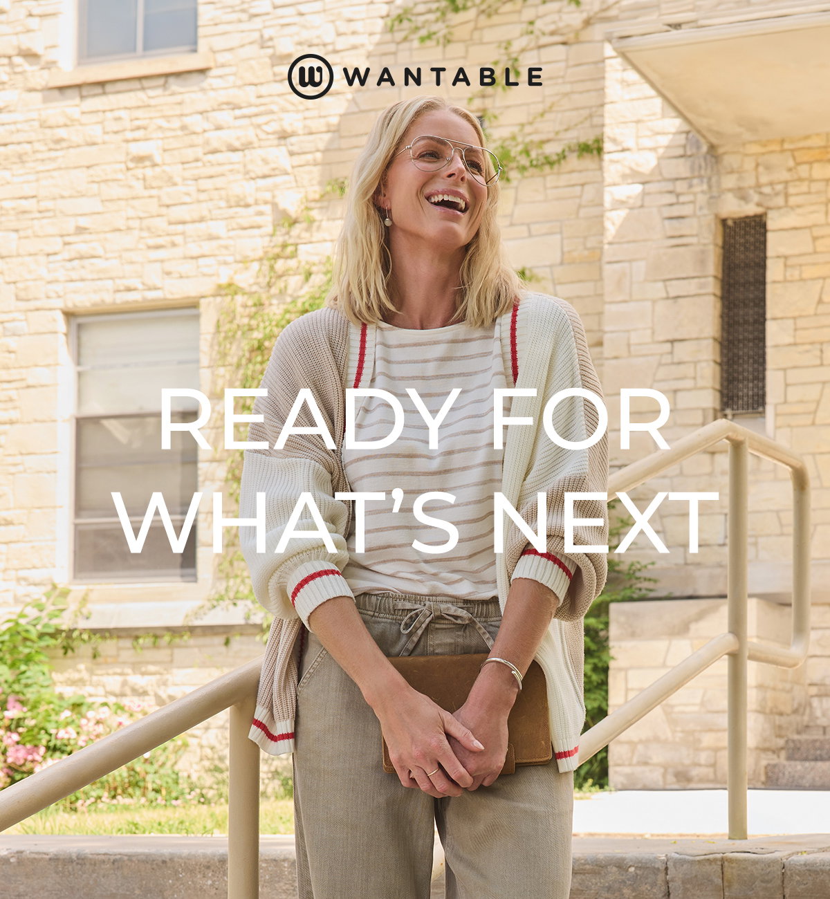 Smiling woman in layered neutral clothing holds a clutch for a back to school look.