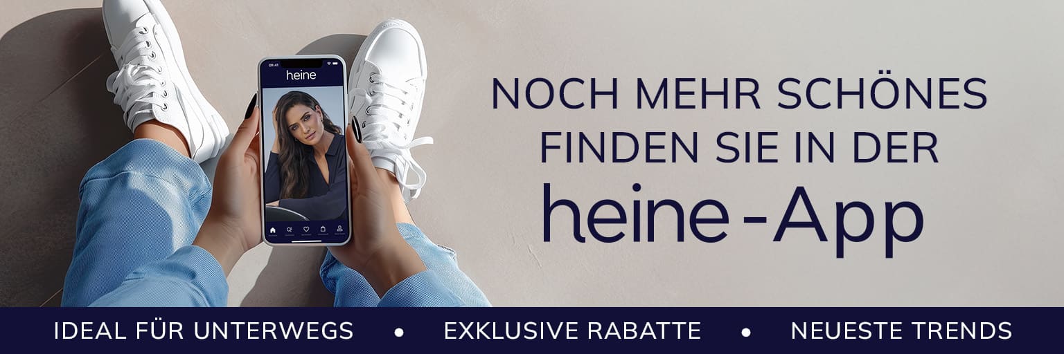 Ein Model hält ein Smartphone mit der heine-App, trägt weisse Sneaker und Jeans. Text: 'Noch mehr Schönes finden Sie in der heine-App. Ideal für unterwegs, exklusive Rabatte, neueste Trends.'