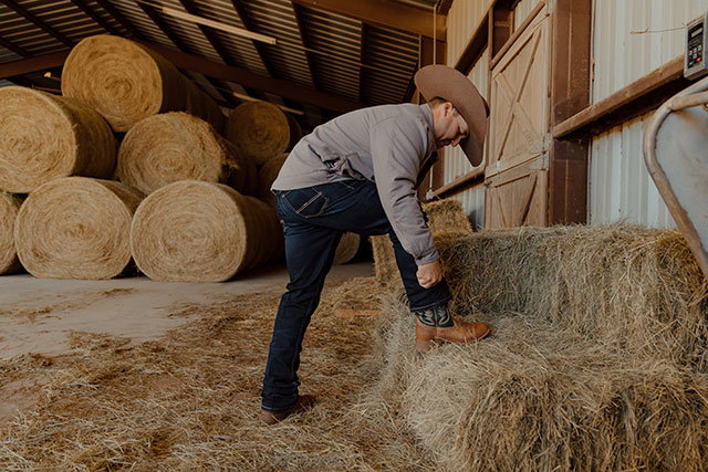 A man wearing Justin Jeans in a barn.