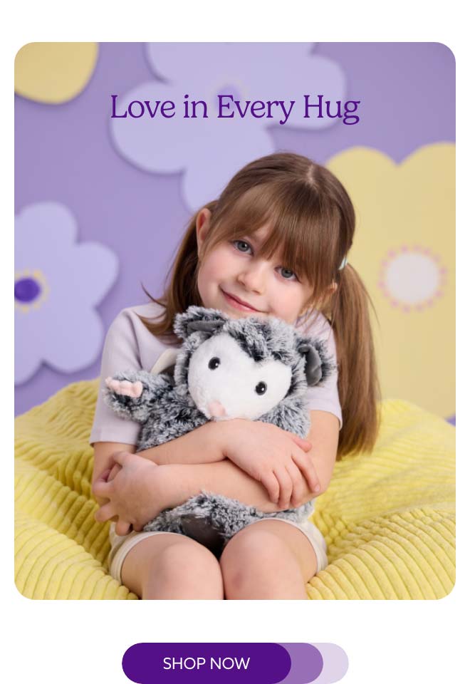 A little girl hugging Opossum Warmies. Shop Now.