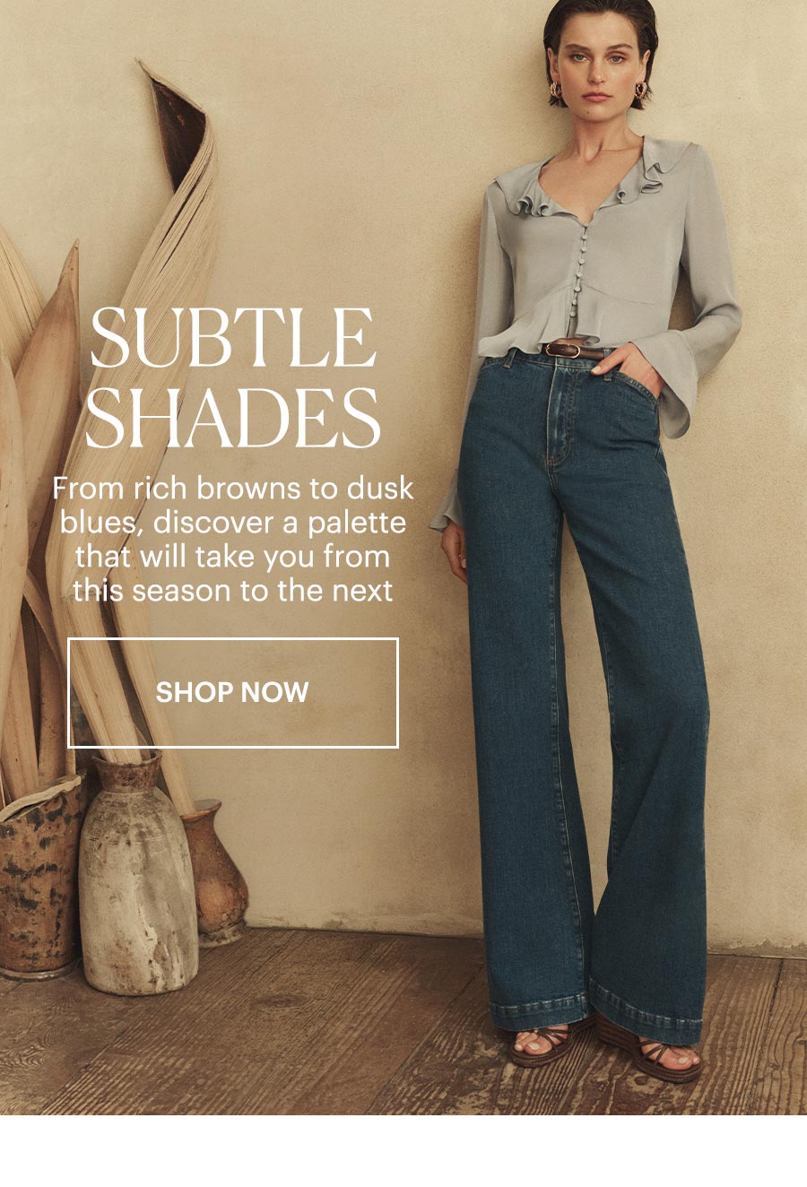 Subtle Shades - From rich browns to dusk blues, discover a palette that will take you from this season to the next. Featuring a woman wearing a light blue long-sleeved ruffle neckline blouse with a pair of dark wash high-rise flare jeans and brown leather wedge sandals. Shop Now.
