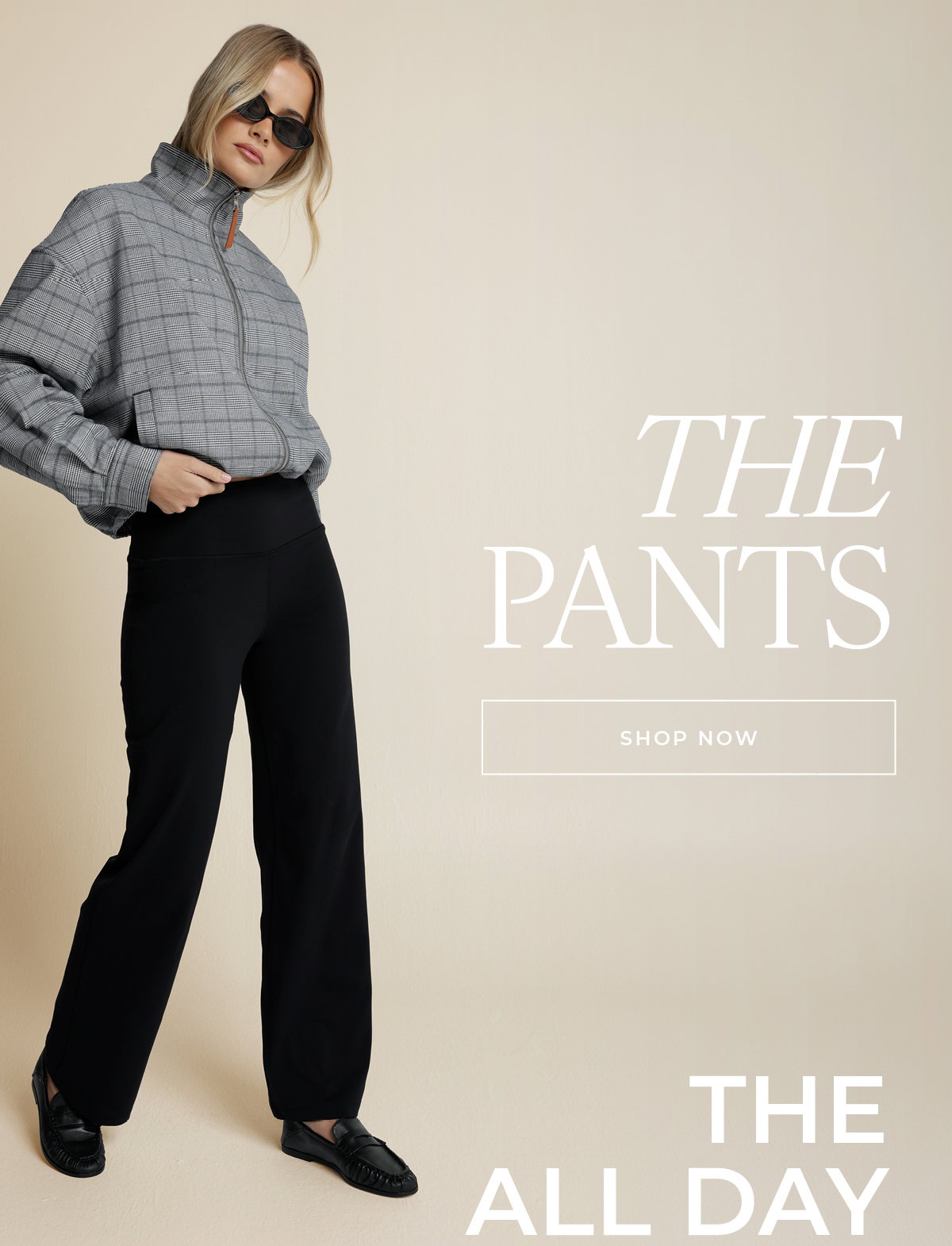 Woman styled in the All Day Active Pant with a checked jacket, text reads "The Pants, The All Day."