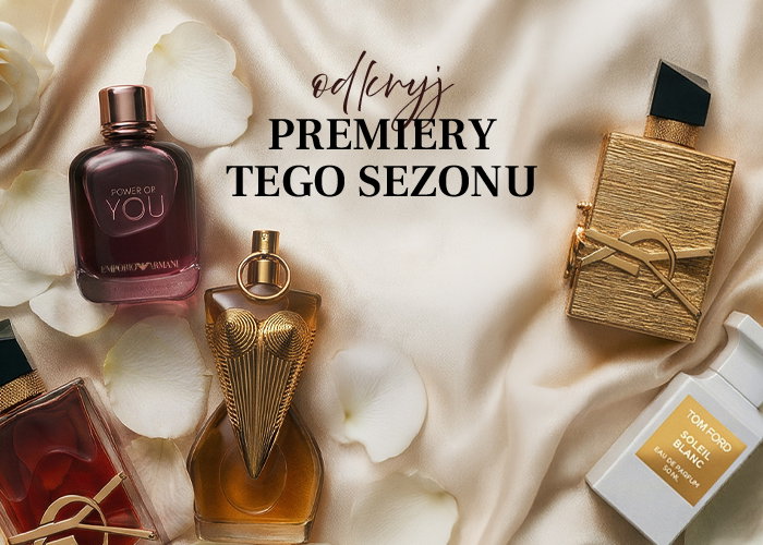 Assortment of luxury perfume bottles on cream silk with rose petals and Polish text 'odkryj PREMIERY TEGO SEZONU'