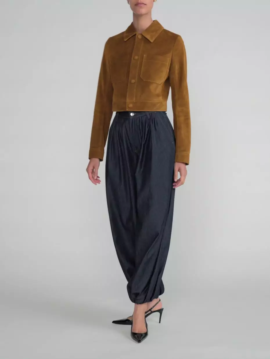 b'The model is wearing The Denim Balloon Pant in Rinse paired with The Small Suede Jacket in Saddle.'