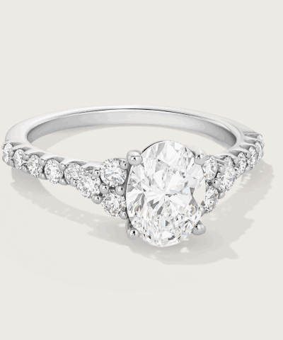 White gold engagement ring featuring an oval diamond center stone and a pavé diamond band.