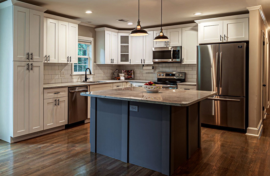 A modern kitchen features stainless steel appliances, white cabinetry and a large center island