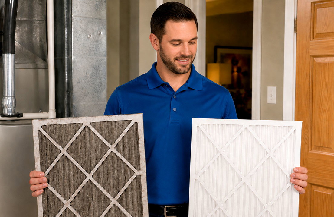 A home service technician compares a dirty furnace air filter with a clean replacement