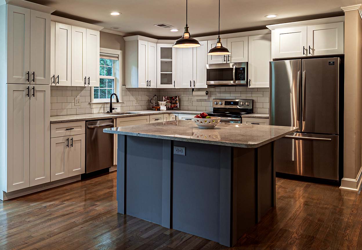A modern kitchen features stainless steel appliances, white cabinetry and a large center island