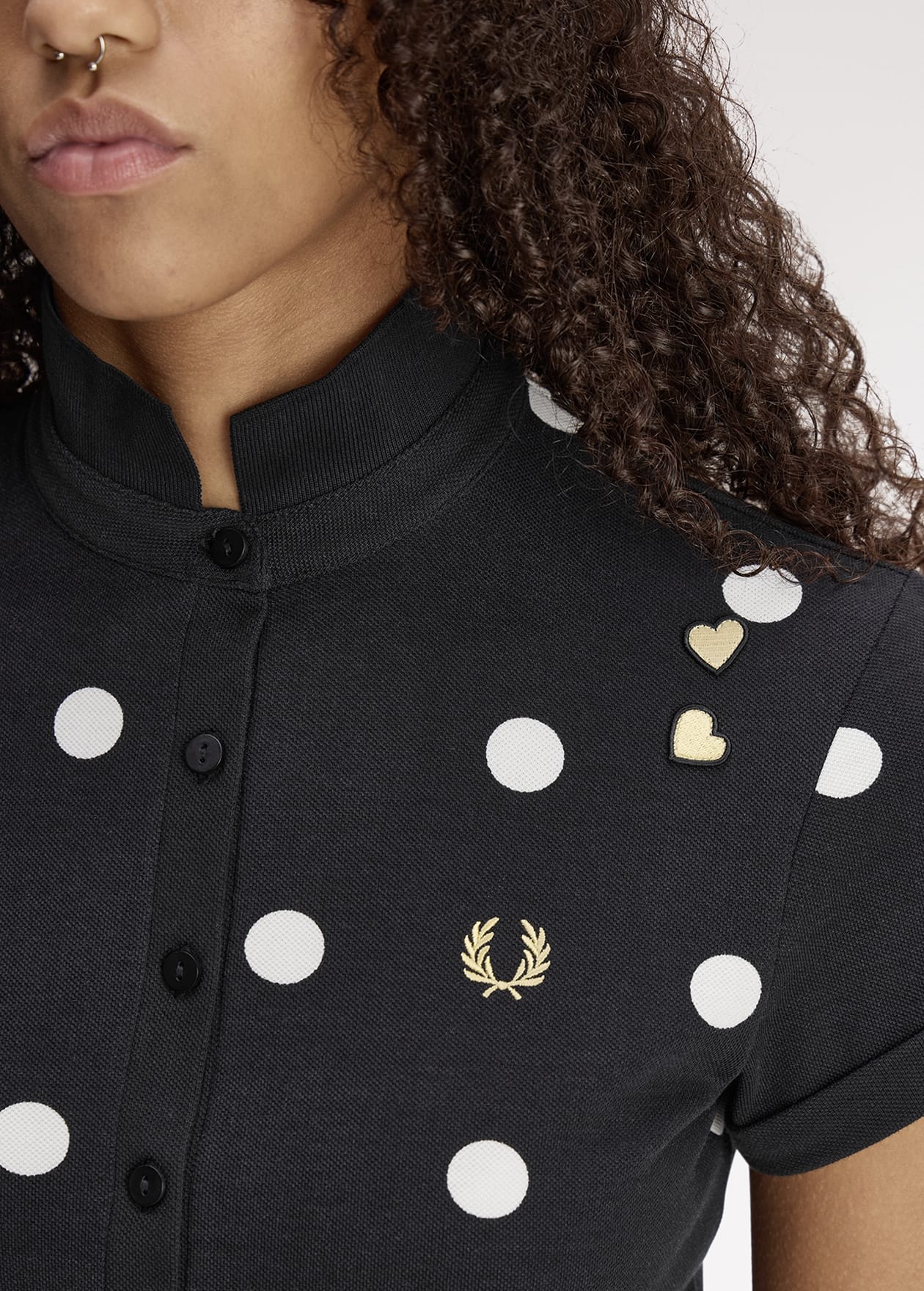 A close up of a female model wearing a Fred Perry x Amy Winehouse Foundation Polka Dot Polo Shirt in Black