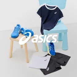 Zapatillas deportivas azules con acentos blancos, camiseta navy con ribete blanco, pantalones cortos negros y camisa blanca sobre superficies claras con una silla azul.