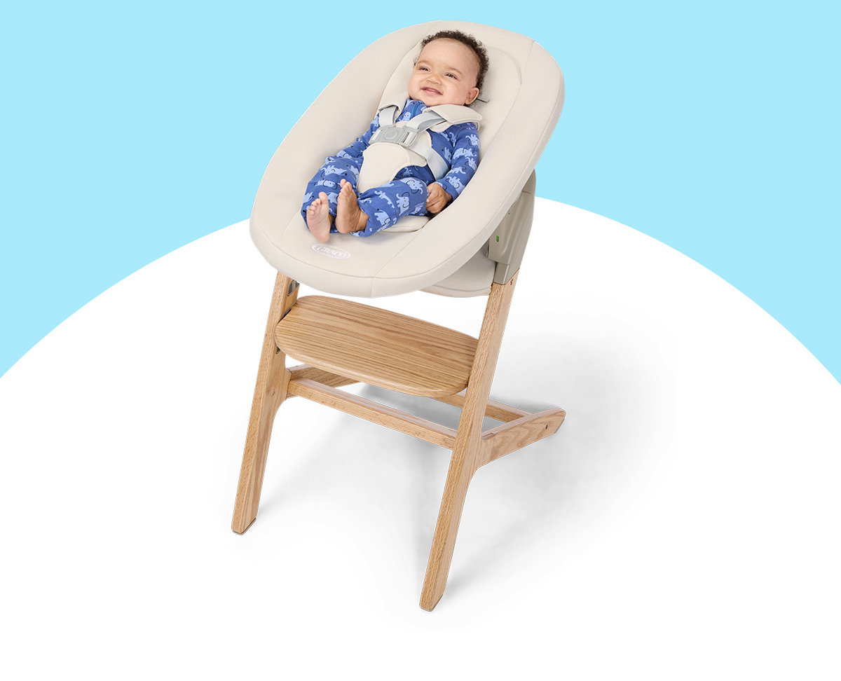 Smiling newborn resting in the Newborn SecureSeat of the Graco Close2Baby 3-in-1 Highchair.