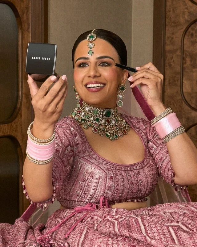 Woman applying Bobbi Brown brow pencil using a pocket mirror.
