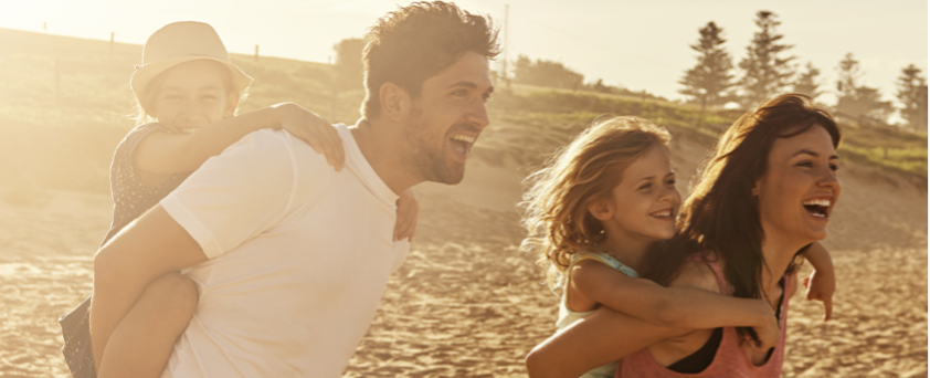 Familie mit zwei Kindern genießt gemeinsam einen sonnigen Tag am Strand.