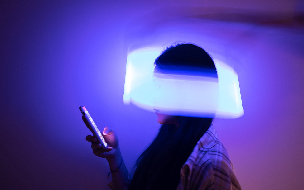 A woman looking at her phone with a swirl of light wrapping around her head