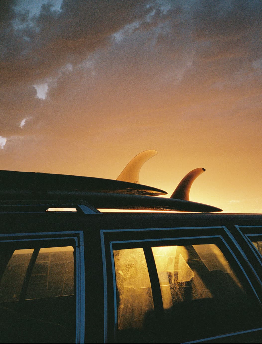 Sunset behind a car with 2 surfboards on top