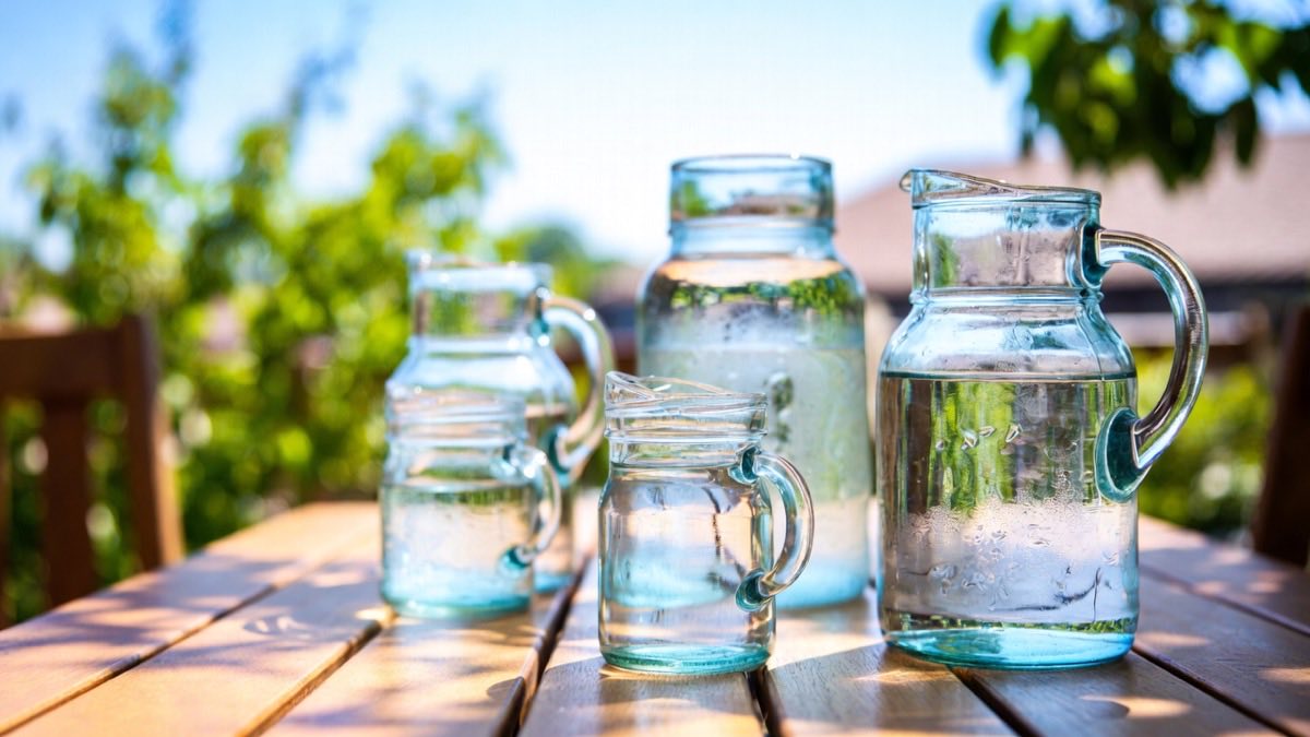 Glazen karaffen met water op een houten tafel in de zon