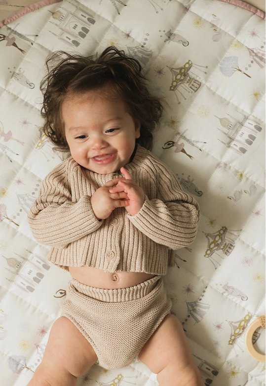 kid laying on play mat smiling at camera