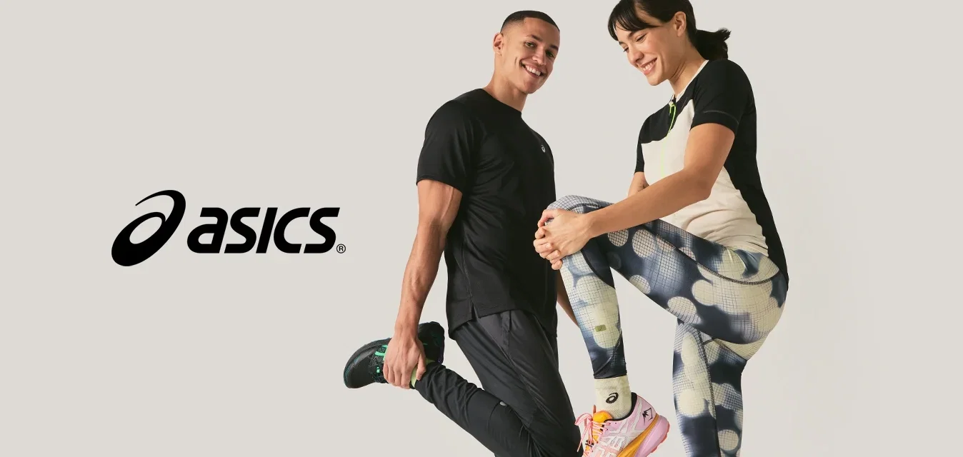 Homme et femme en tenue de sport souriant tout en s'étirant les jambes sur un fond clair uni.