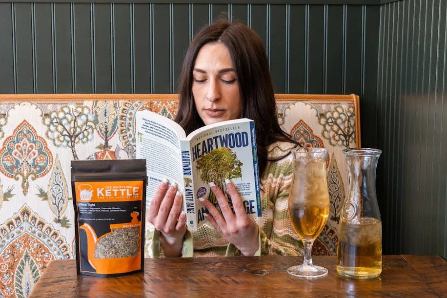 girl holding heartwood book and iced sleep tight tea