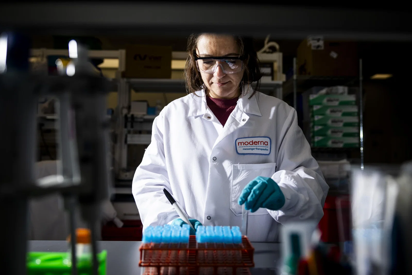 A woman scientist in a white lab coat works with vials of flu vaccine at a Moderna laboratory.