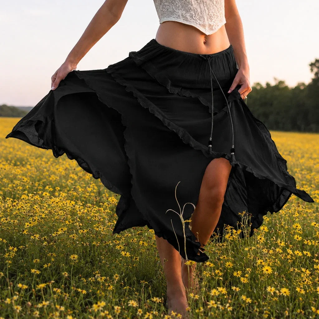 Woman in flowing black skirt twirling in golden wildflower field at sunset, wearing cream crop top