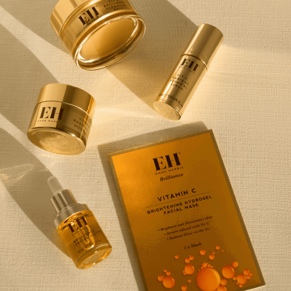 Emma Hardie Brilliance skincare products arranged on a warm golden background.