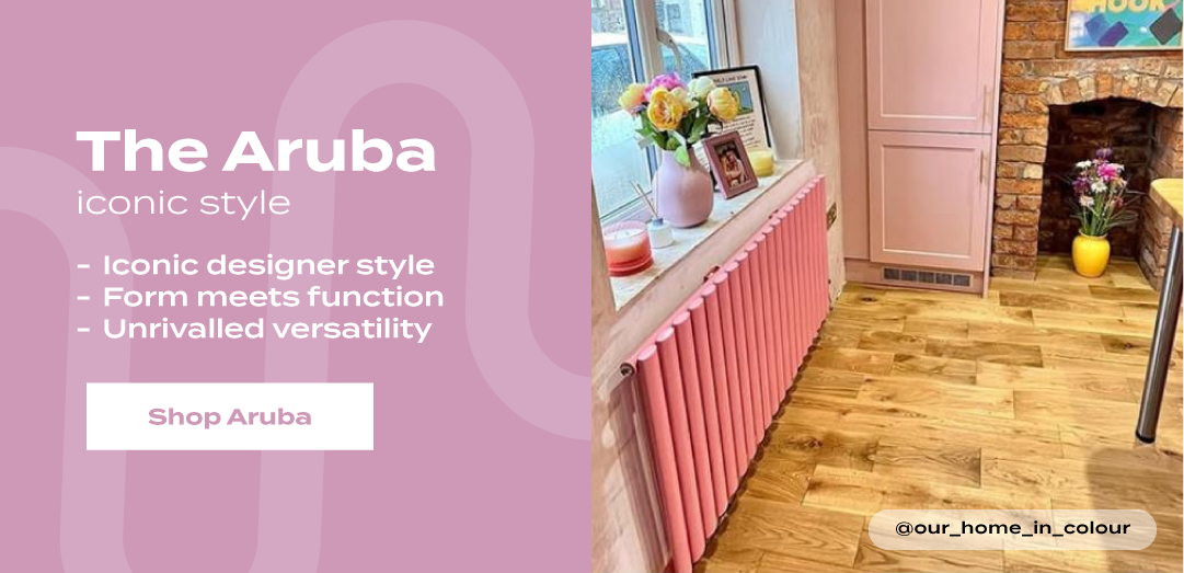The Aruba pink vertical designer radiator beneath a window in a pastel kitchen, with text highlighting its iconic style, functional design, and versatile appeal.