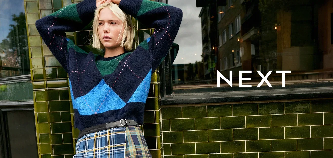 Navy, groene en blauwe geblokte trui met een losse pasvorm, gecombineerd met een geplooide geruite rok met gele accenten en een zwarte riem.
