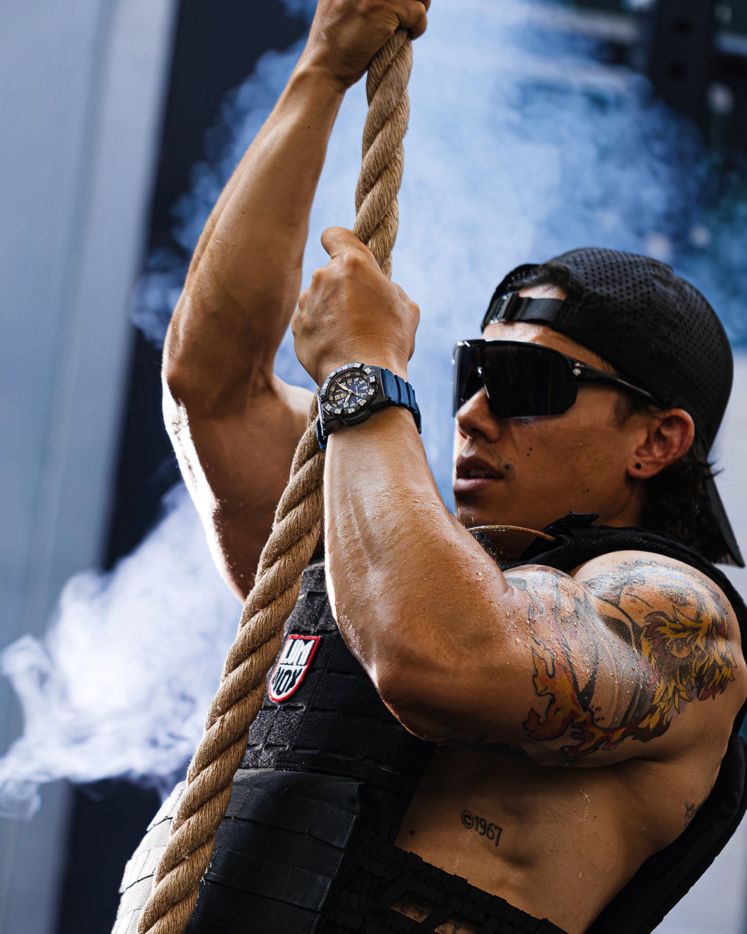 Man sitting in the gym with a backwards hat with watch on wrist