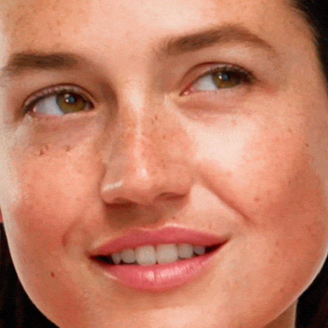 Close-up of a woman face, smiling and showing glowing skin.