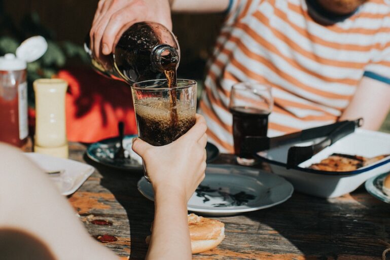 Un jeune homme remplit un verre d'une boisson sucrée