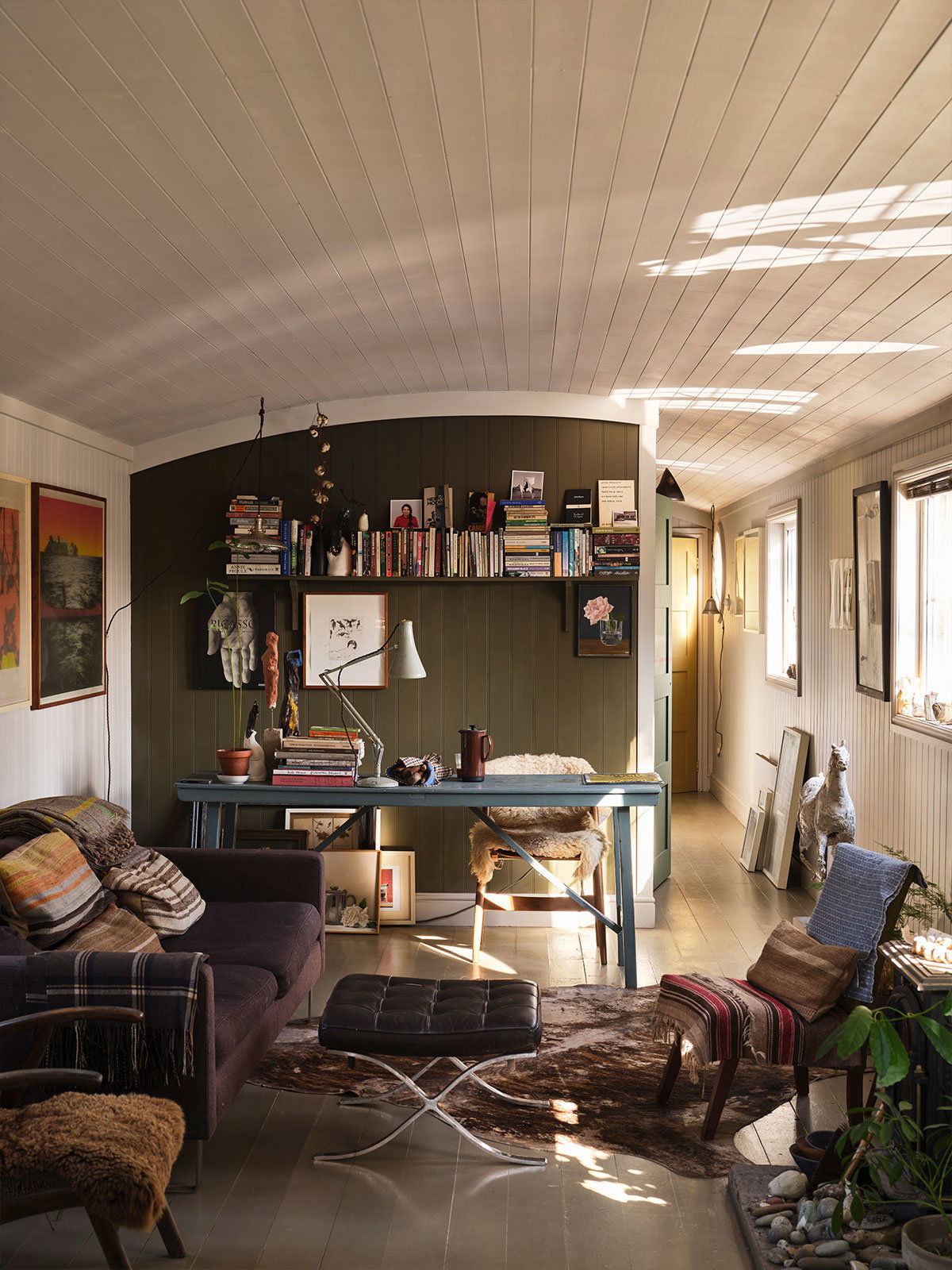 Cosy living room with white ceiling, olive wall, bookshelves, and eclectic vintage furniture.