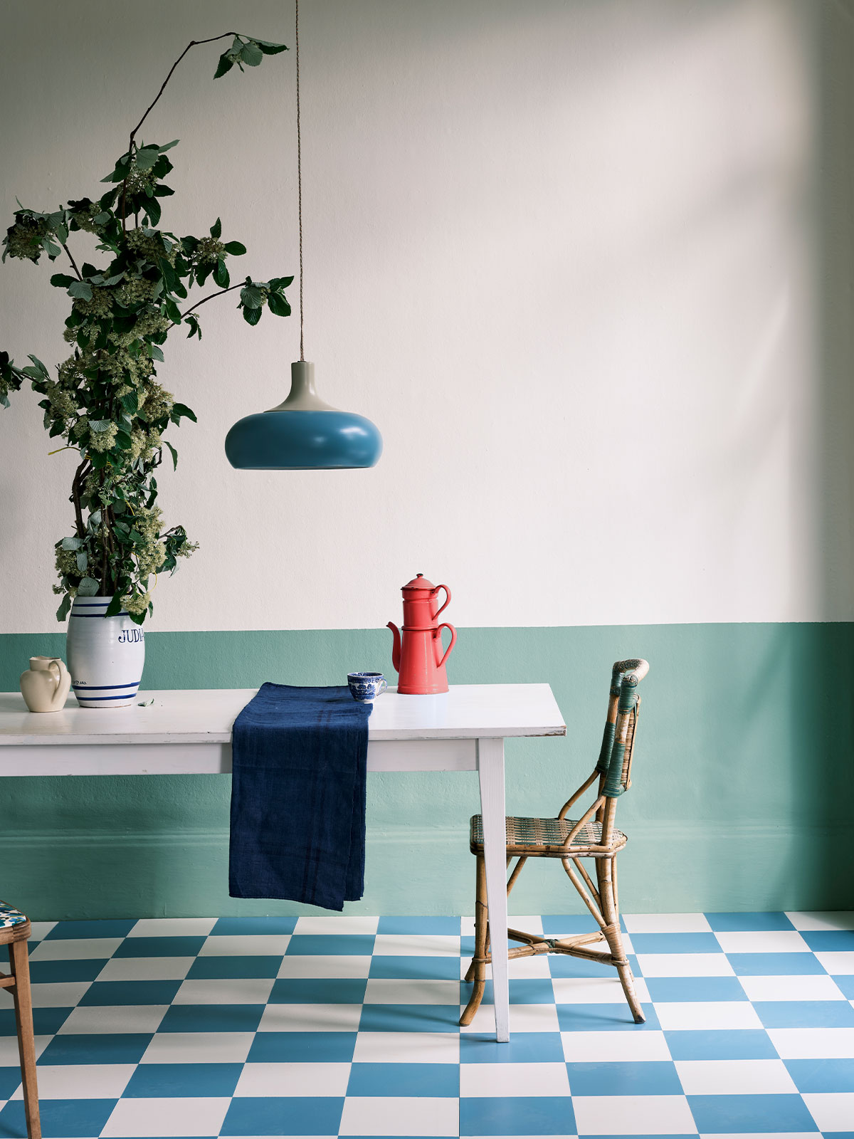 Fresh mint and cream kitchen with blue pendant light, white table, and checkerboard floor.