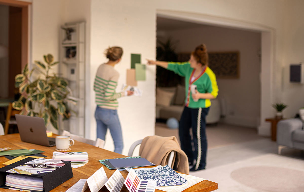 Two people choosing paint colours in a bright workspace with samples and design materials.
