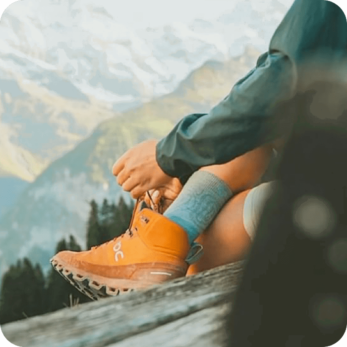 A person sitting on a log lacing up their boots