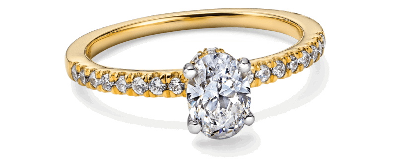 Yellow gold oval diamond solitaire engagement ring in four-prong setting and pavé diamonds along the band.