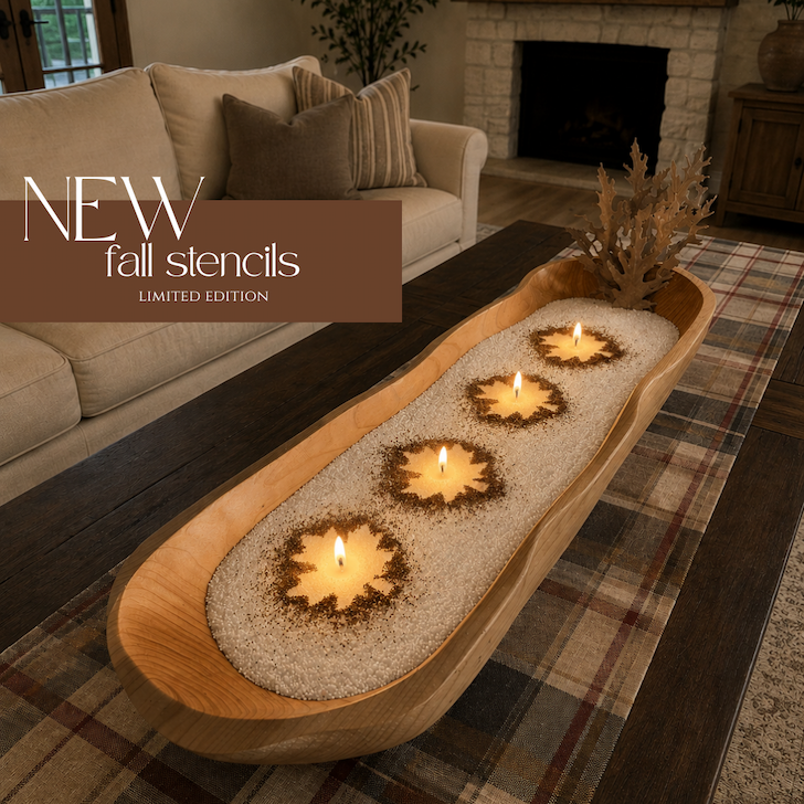 Long wooden dough bowl filled with pearled candle wax featuring four lit maple leaf-shaped candles. Text reads: "NEW fall stencils – Limited Edition." Cozy fall living room with plaid table runner and neutral décor in the background.