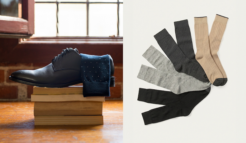 Split image. Left: a black dress shoe with a navy polka-dot sock draped over it, both resting on a stack of old books in front of a window with brick and wood surroundings. Right: four pairs of dress socks fanned out — light gray, dark charcoal, tan, and black.