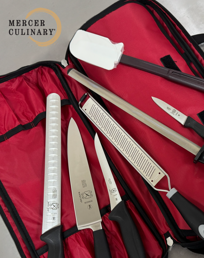 Mercer Culinary knife kit opened to display chef knives, honing steel, grater, spatula, and blade guards organized inside a red carrying case.