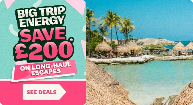 Travel promotion graphic featuring the text “BIG TRIP ENERGY” and “SAVE £200* ON LONG-HAUL ESCAPES” in bold lettering on a turquoise background, with a pink and white “SEE DEALS” button below. To the right, a tropical beach scene shows clear turquoise water, palm trees, thatched-roof cabanas, sun loungers, and a bright blue sky, suggesting a warm long-haul holiday destination.