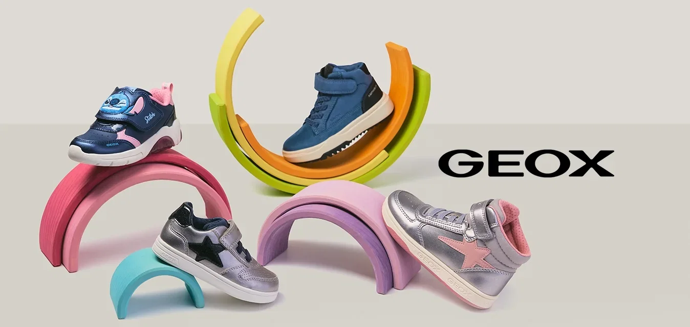 Vier kleurrijke kindersneakers gepresenteerd op pastelkleurige, regenboogvormige standaards tegen een lichte achtergrond.
