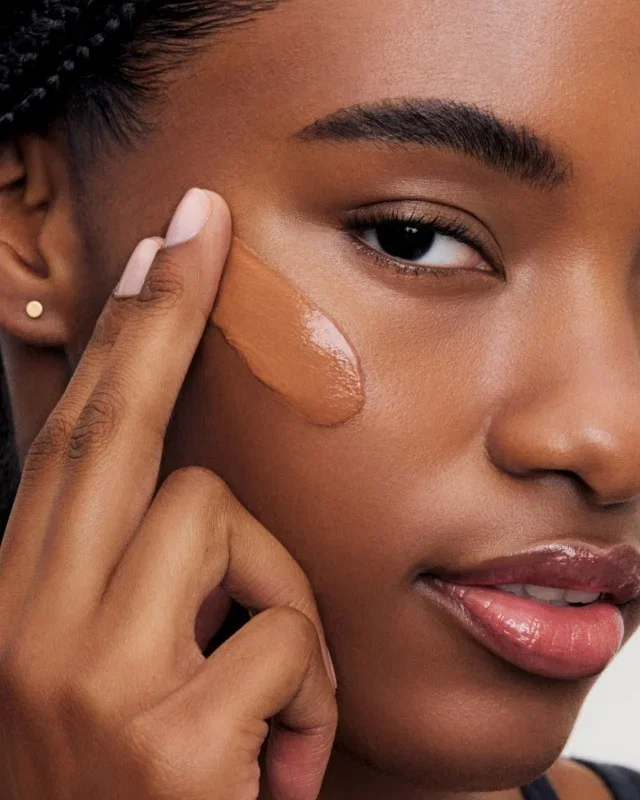 Woman applying Vitamin Enriched Skin Tint to her cheek.