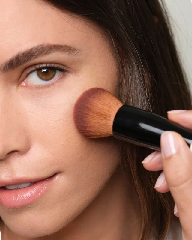 Woman applying Weightless Skin Foundation to her cheek.