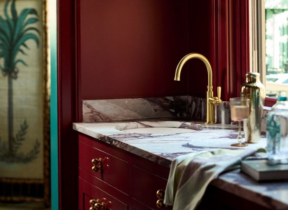 Dabito’s bold burgundy wet bar featuring a Porto Fino bar sink and Vibrant Brushed Moderne Brass faucet, styled with glassware and bottles.