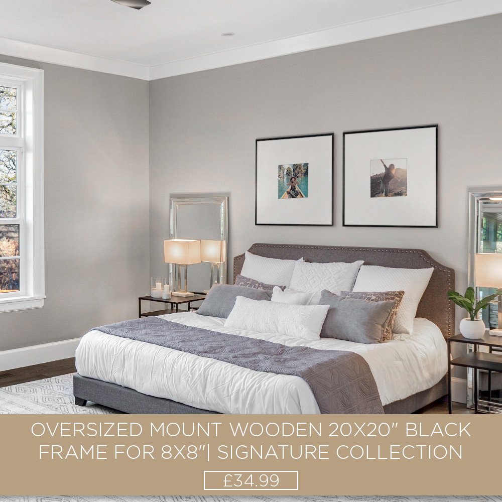 Two black oversized mount photo frames displayed above a bed in a stylish, neutral-toned bedroom.