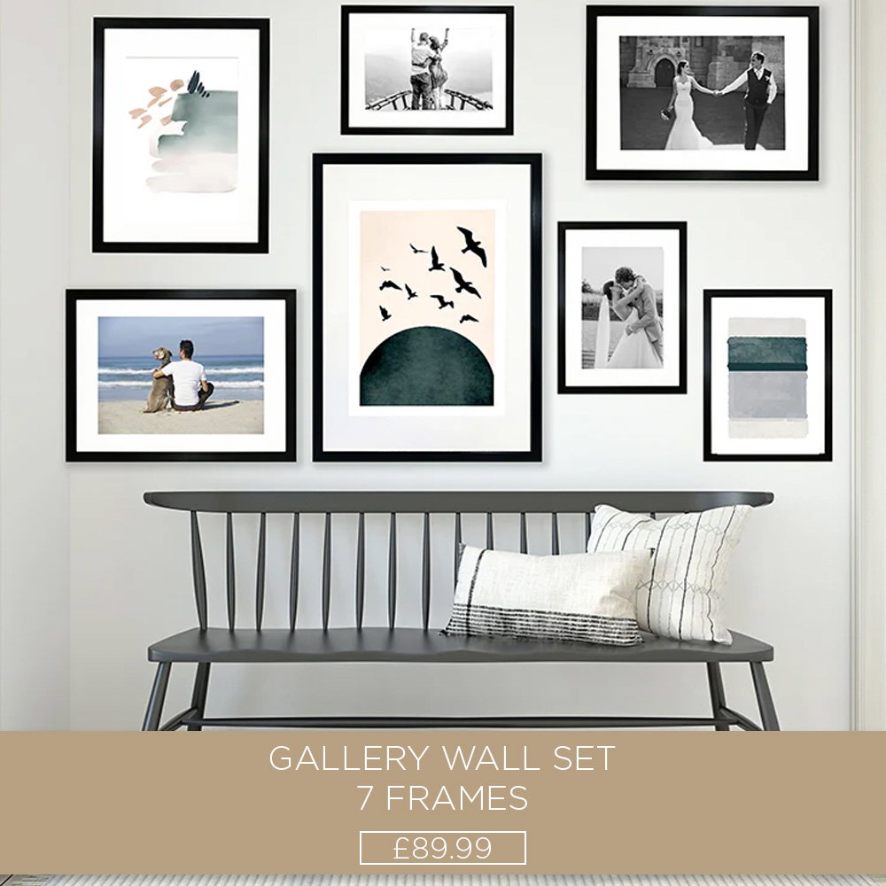 Seven-piece black gallery wall frame set featuring artwork and family photos displayed above a hallway bench.