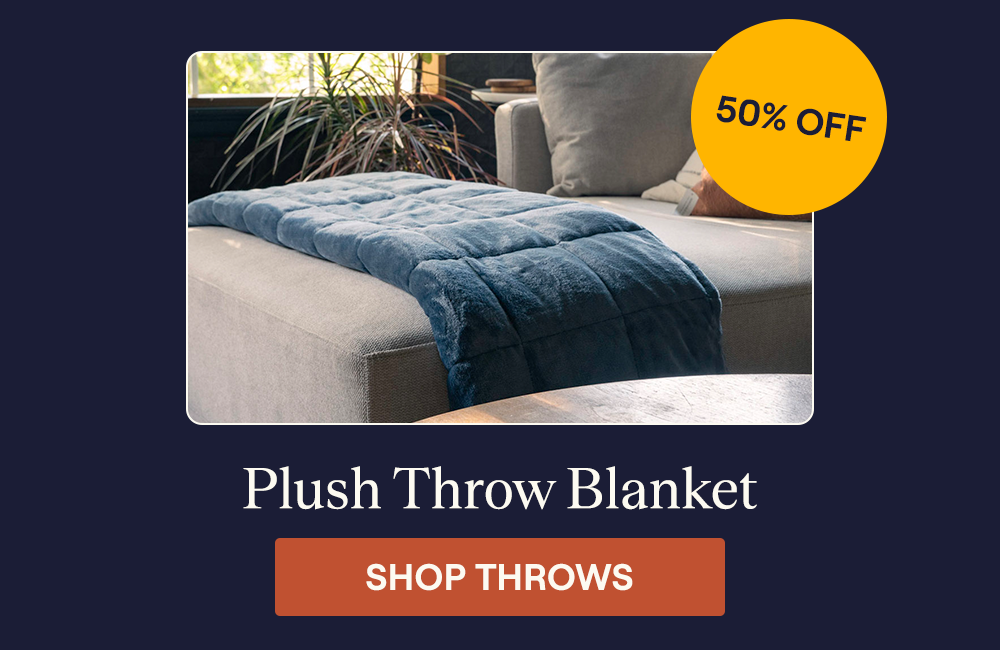 The Plush Throw Blanket laying on the edge of a couch folded